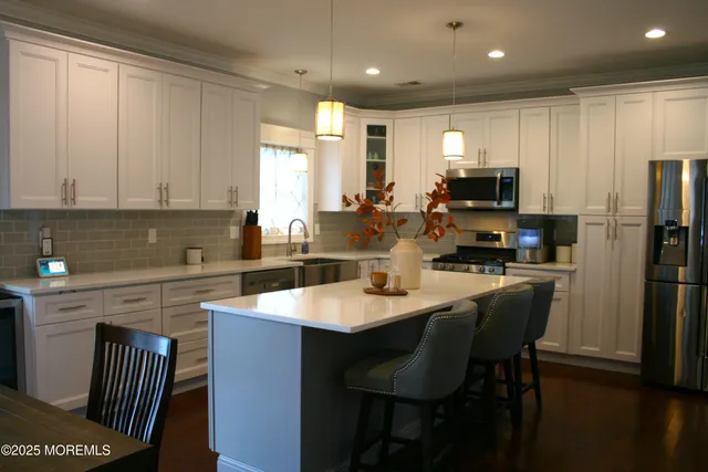 a kitchen with kitchen island granite countertop a sink a stove a refrigerator cabinets and a dining table