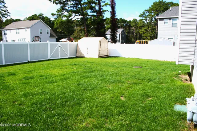 a view of a white house with a small yard and large tree
