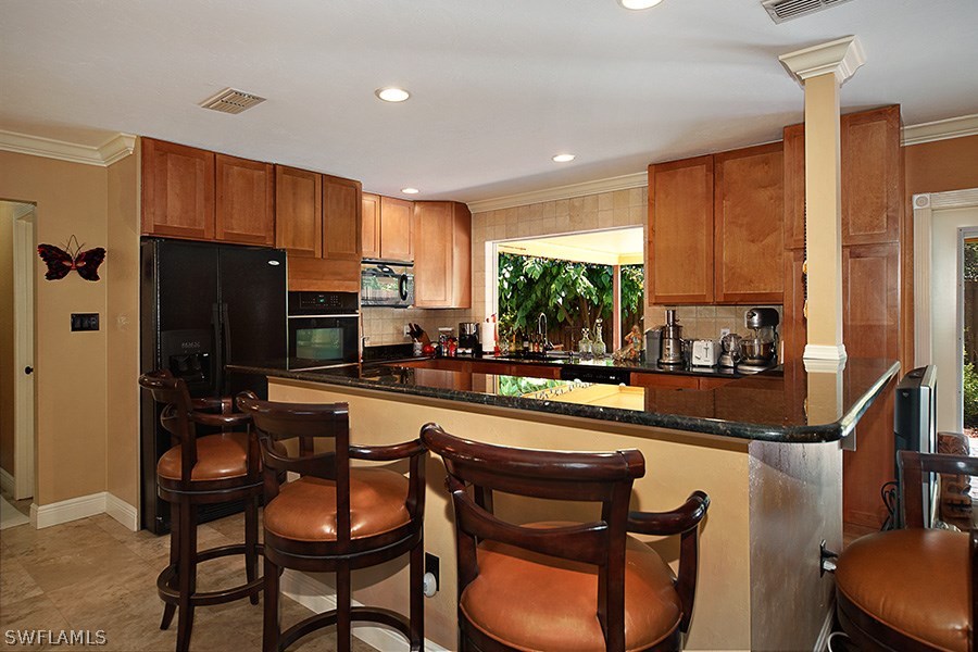 944 Robalo Drive Fort Myers, FL 33919 - Photo 5 of 14 a kitchen with sink refrigerator dining table and chairs