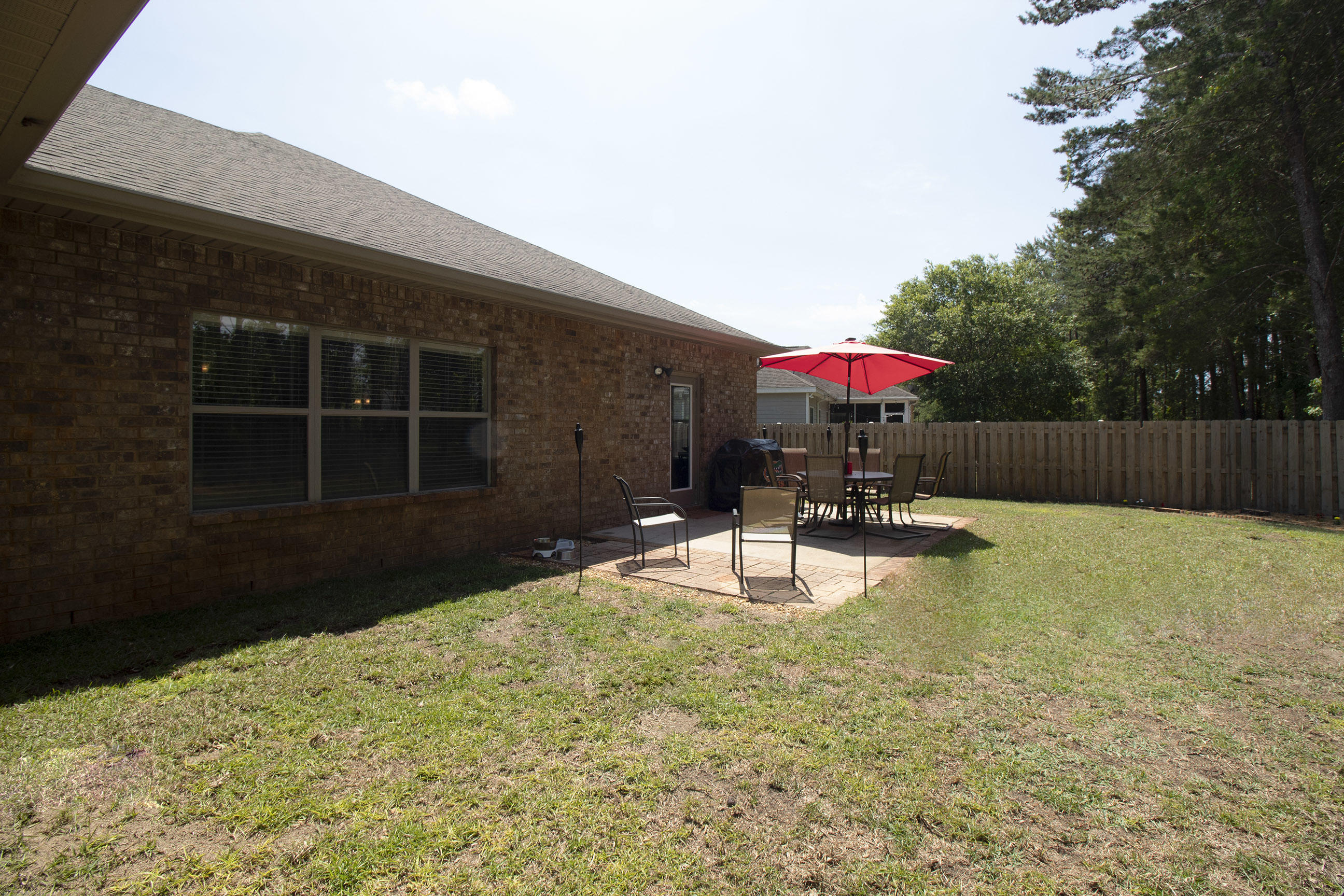 206 Mango Lane Freeport, FL 32439 - Photo 33 of 45 a view of a backyard with table and chairs under an umbrella with wooden fence