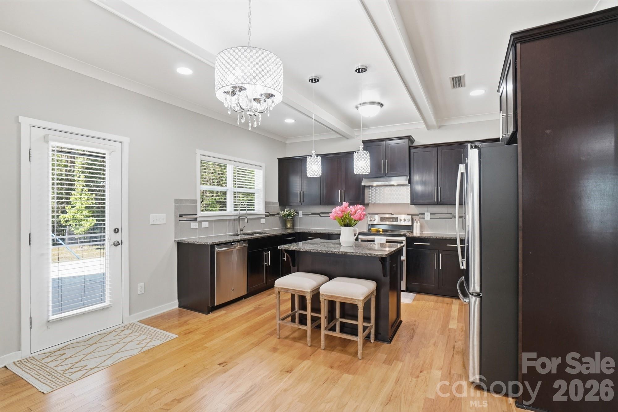 2153 Bluebell Way Tega Cay, SC 29708 - Photo 16 of 48 a kitchen with stainless steel appliances granite countertop a stove refrigerator a dining table and chairs with wooden floor
