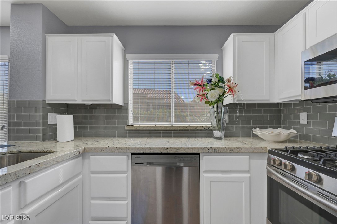 Undisclosed Address Las Vegas, NV 89134 - Photo 24 of 39 Kitchen with appliances with stainless steel finishes, white cabinetry, and decorative backsplash