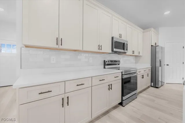 a kitchen with stainless steel appliances granite countertop white cabinets a sink a stove a refrigerator and white cabinets