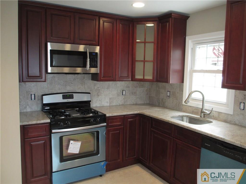 77 Middle Hill Road Colonia, NJ 07067 - Photo 3 of 21 a kitchen with stainless steel appliances a stove a microwave a sink and cabinets