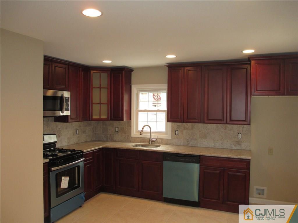 77 Middle Hill Road Colonia, NJ 07067 - Photo 4 of 21 a kitchen with wooden cabinets and stainless steel appliances