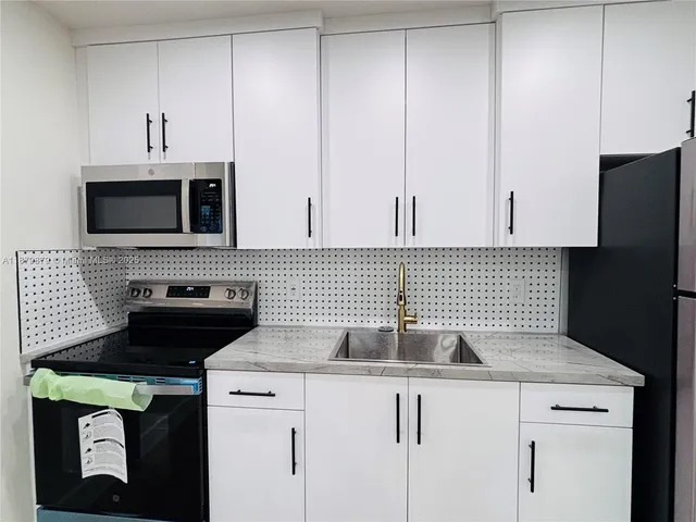 a kitchen with appliances a sink and cabinets