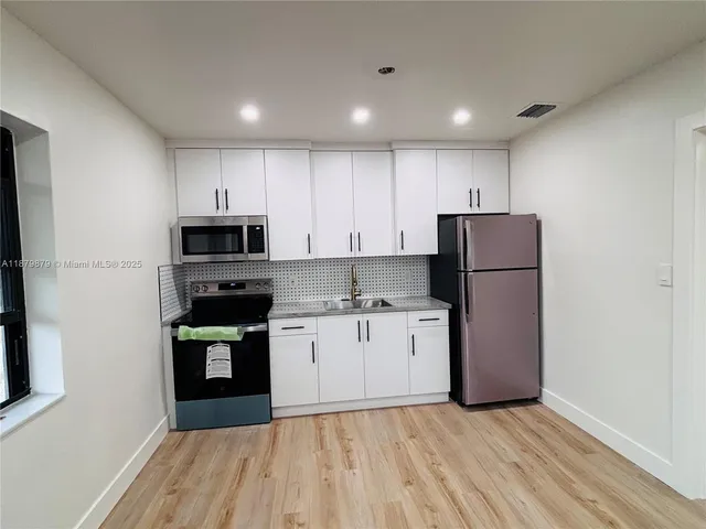 a kitchen with white cabinets and stainless steel appliances