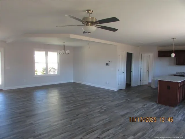 an empty room with wooden floor a ceiling fan and windows
