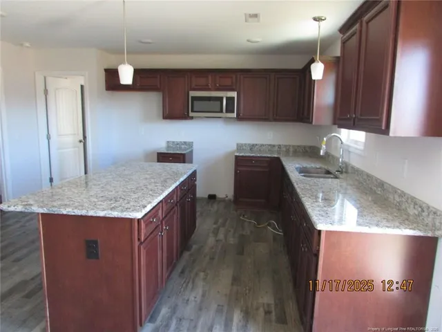 a kitchen with kitchen island granite countertop wooden cabinets a sink and dishwasher
