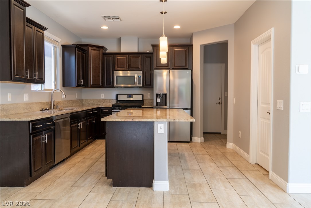 11045 Elk Sands Road Las Vegas, NV 89179 - Photo 12 of 67 Rich dark cabinetry and stone countertops anchor this functional kitchen space with tile flooring.