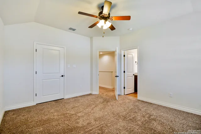 a view of an empty room with chandelier fan