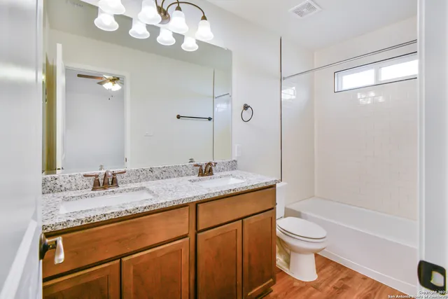 a bathroom with a granite countertop sink a toilet and a mirror