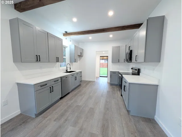 a large white kitchen with a sink a refrigerator and wooden cabinets