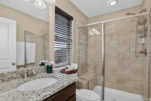a bathroom with a granite countertop sink toilet and shower