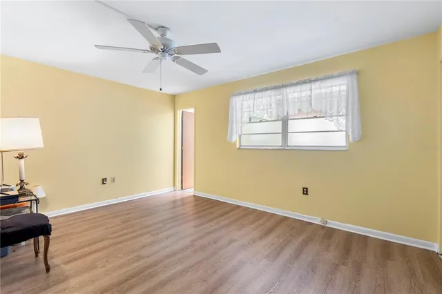 an empty room with wooden floor fan and windows