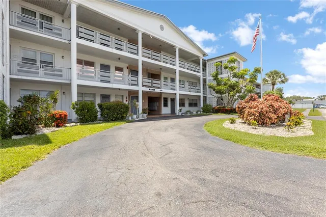 a front view of a building with garden and trees