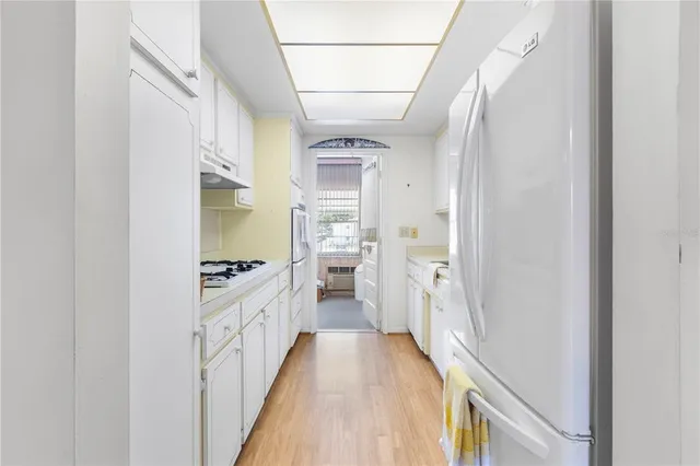 a hallway with white cabinets and wooden floor