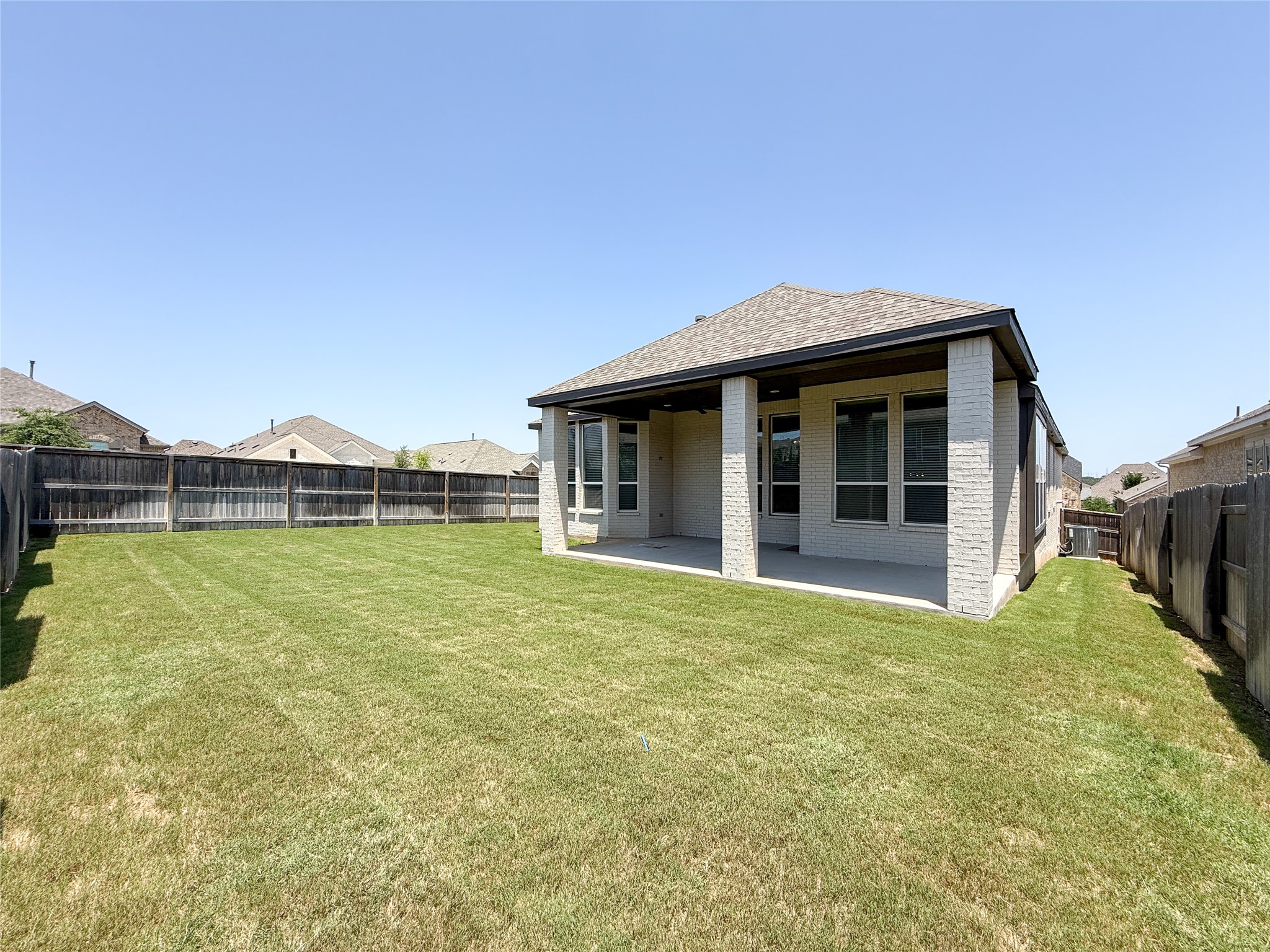 249 Heartleaf Road San Marcos, TX 78666 - Photo 35 of 38 A deep green lawn surrounds a modern brick dwelling, featuring an inviting covered patio for outdoor enjoyment.
