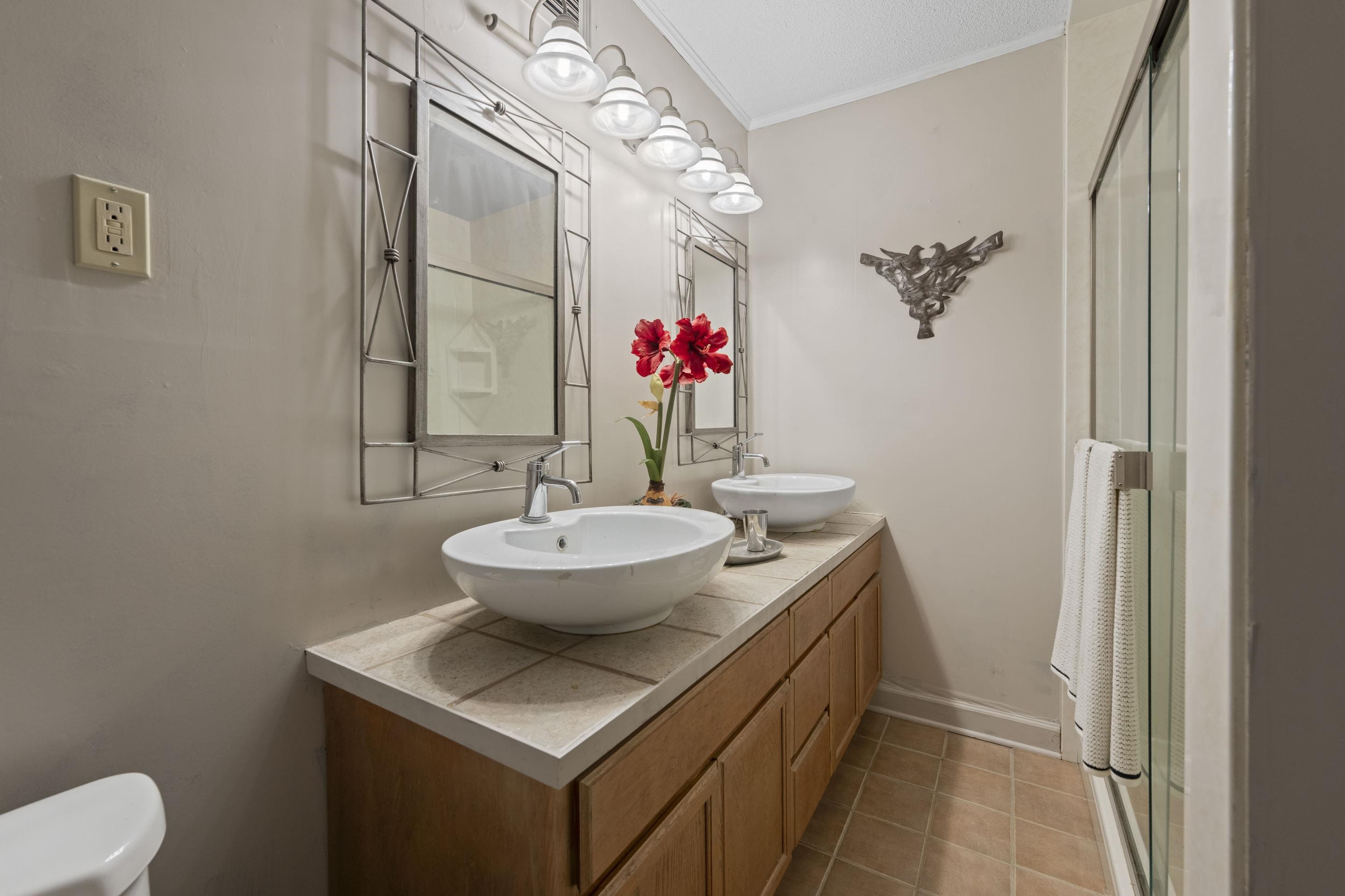 219 North Rose Road Memphis, TN 38117 - Photo 17 of 30 Updated bathroom with dual vessel sinks, elongated vanity, tile flooring, walk-in shower, and modern fixtures.