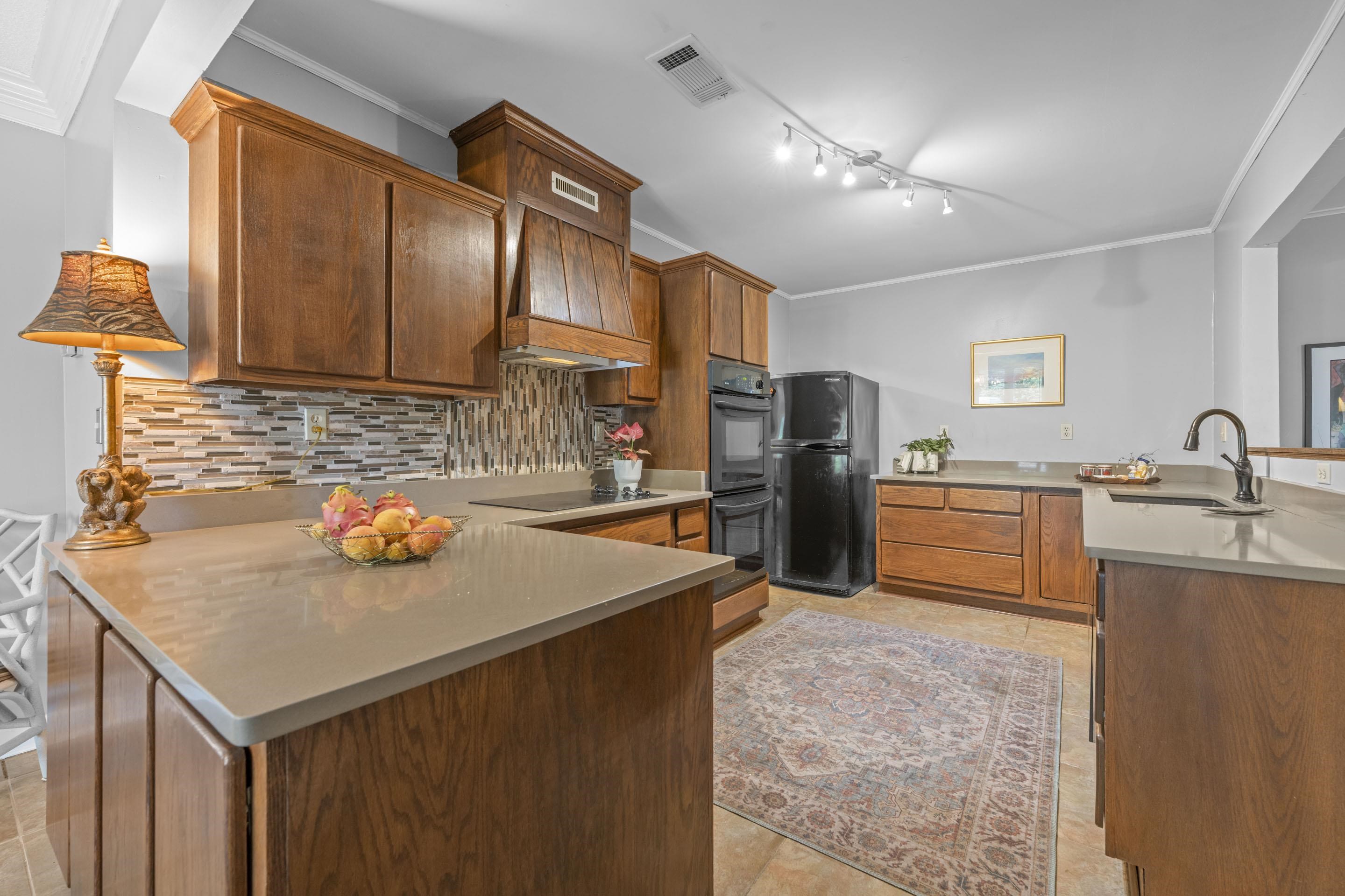 219 North Rose Road Memphis, TN 38117 - Photo 7 of 30 The eat-in kitchen is a chef’s delight, featuring stylish tile flooring, decorative backsplash, solid surface countertops, a cooktop, double oven, dishwasher, and generous cabinet space.