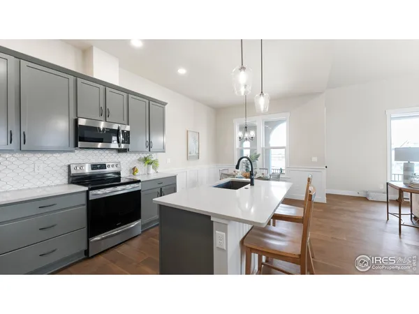 a kitchen with a sink a stove a refrigerator cabinets and a dining table