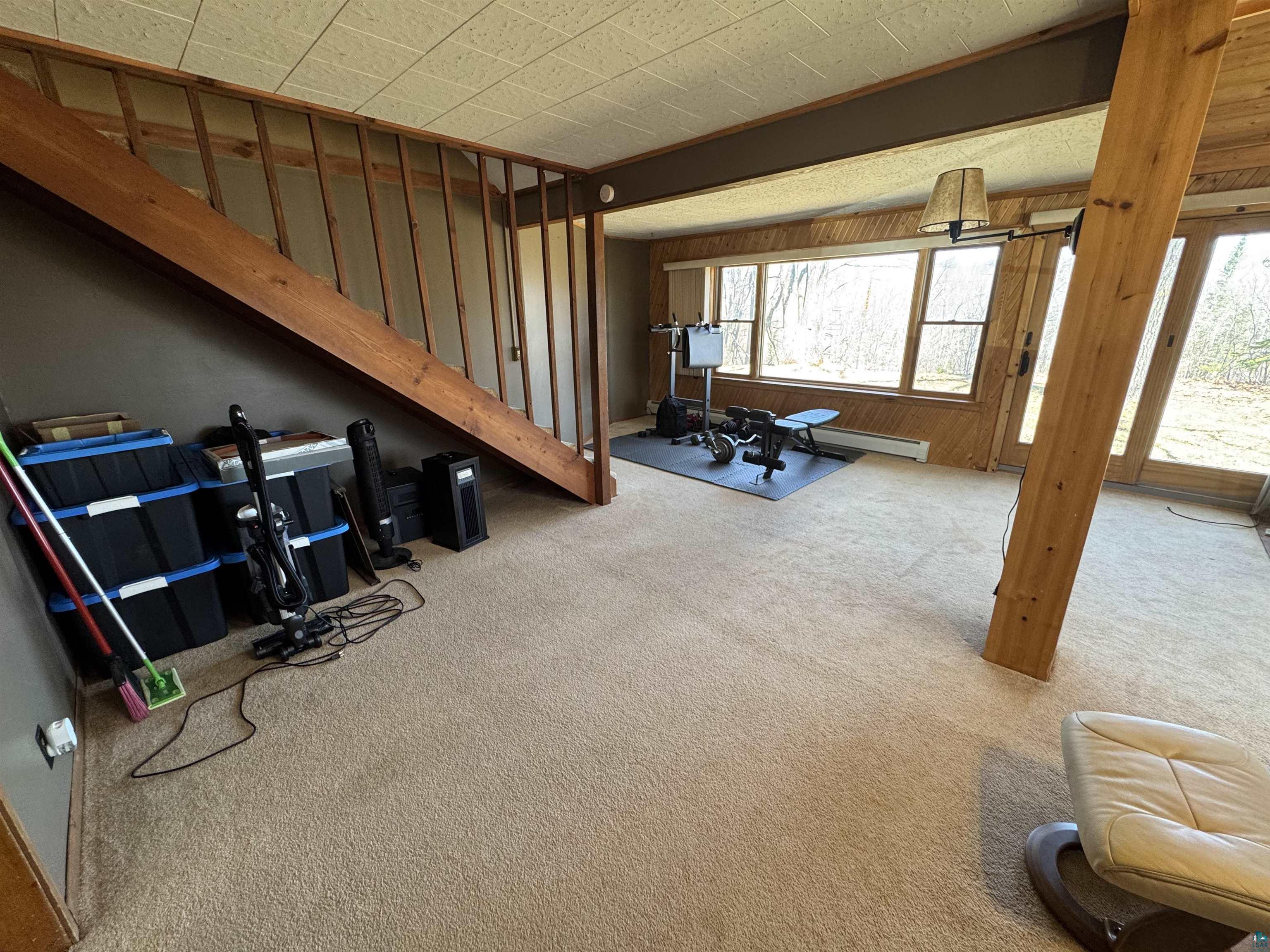 4897 Swanson Drive Maple, WI 54854 - Photo 13 of 25 Spacious room featuring light-toned carpeting and a prominent wooden staircase