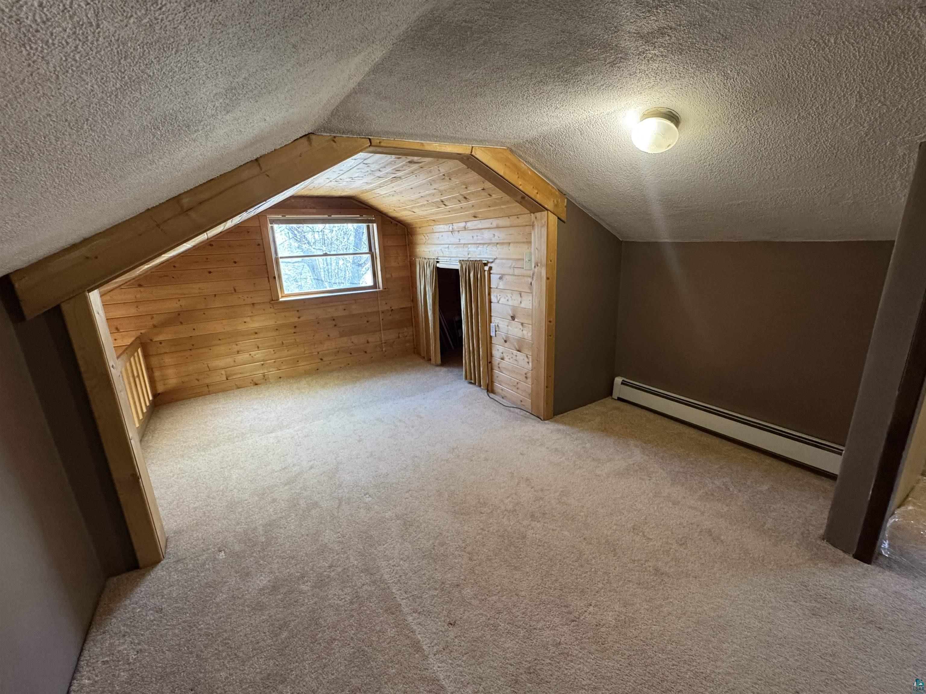 4897 Swanson Drive Maple, WI 54854 - Photo 16 of 25 Carpeted bonus room featuring a sloped ceiling, wood-paneled accent wall, a single window, and baseboard heating