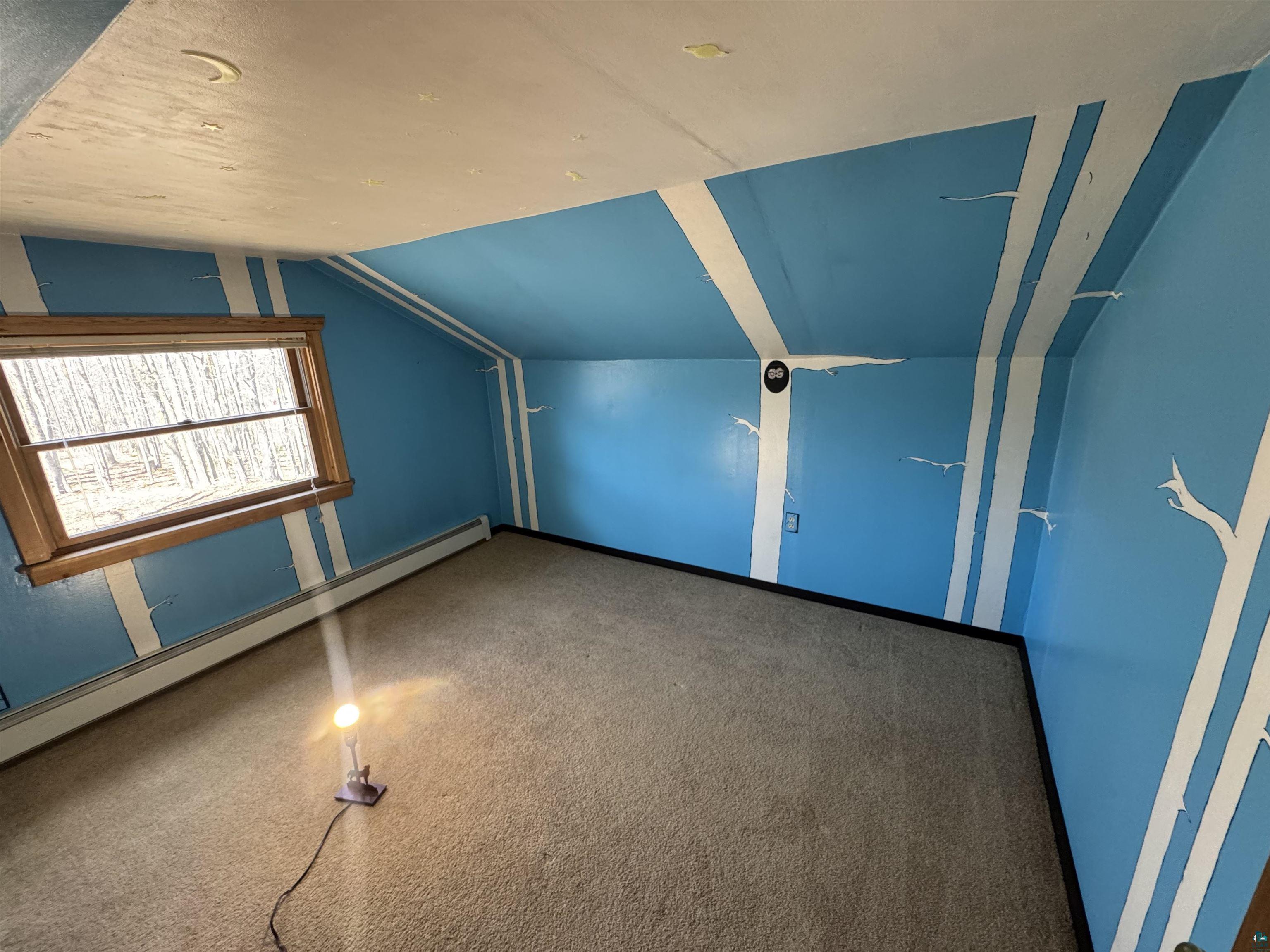 4897 Swanson Drive Maple, WI 54854 - Photo 18 of 25 Carpeted upper bedroom featuring a wood-trimmed window, baseboard heating, and blue walls with white stripe detailing