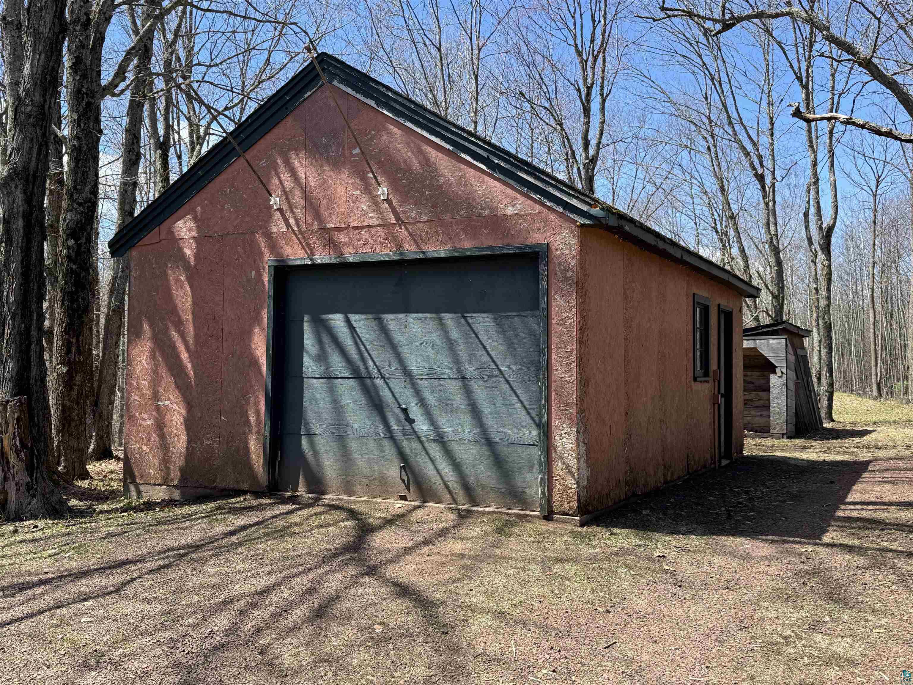 4897 Swanson Drive Maple, WI 54854 - Photo 21 of 25 Detached garage building featuring a roll-up door, side entry door, and two windows