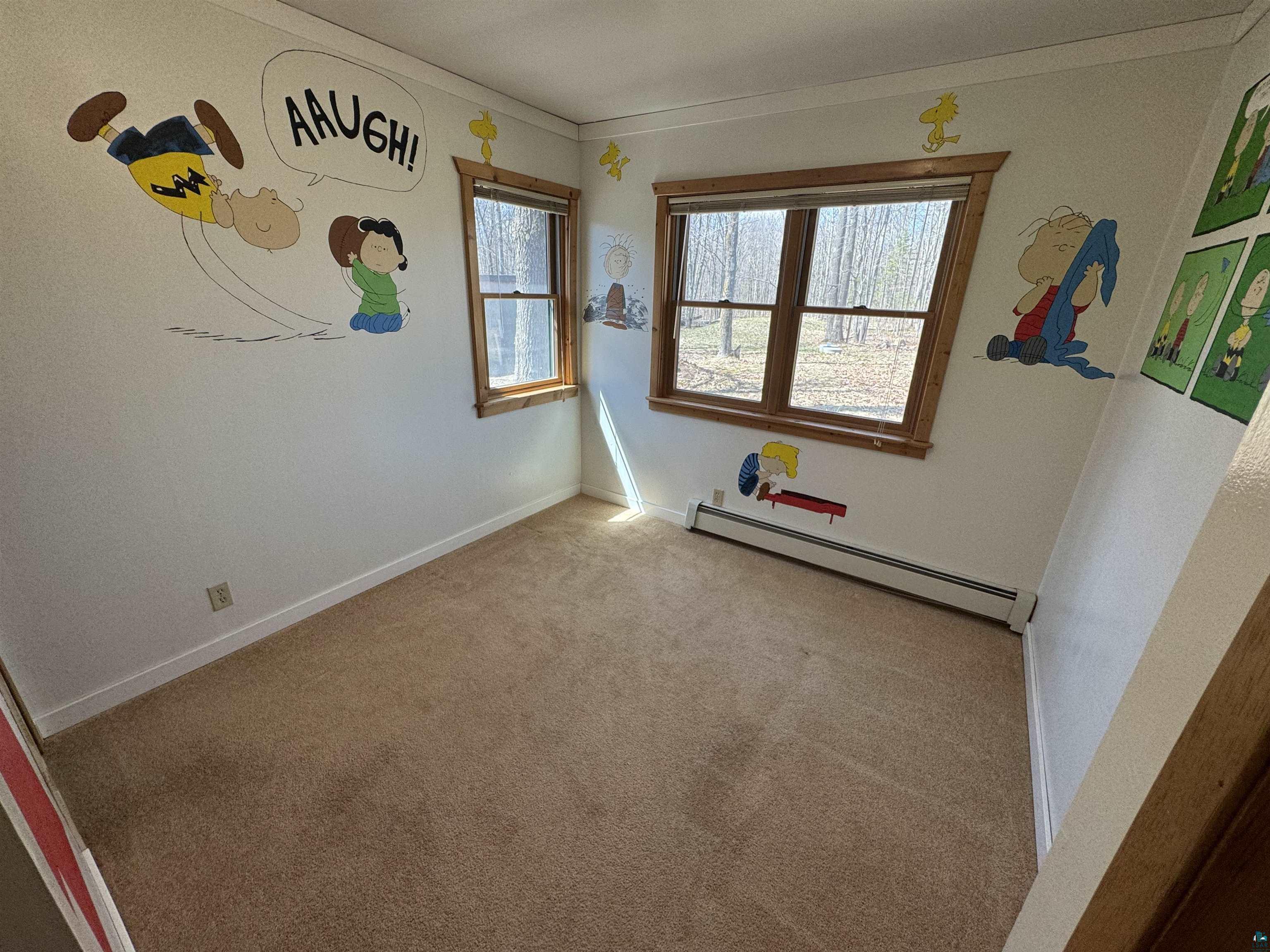 4897 Swanson Drive Maple, WI 54854 - Photo 7 of 25 Carpeted main floor bedroom featuring white walls, two windows with wood trim, and a baseboard heating unit
