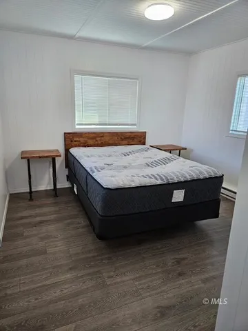 a spacious bedroom with a bed and wooden floor