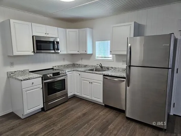a kitchen with cabinets stainless steel appliances and wooden floor