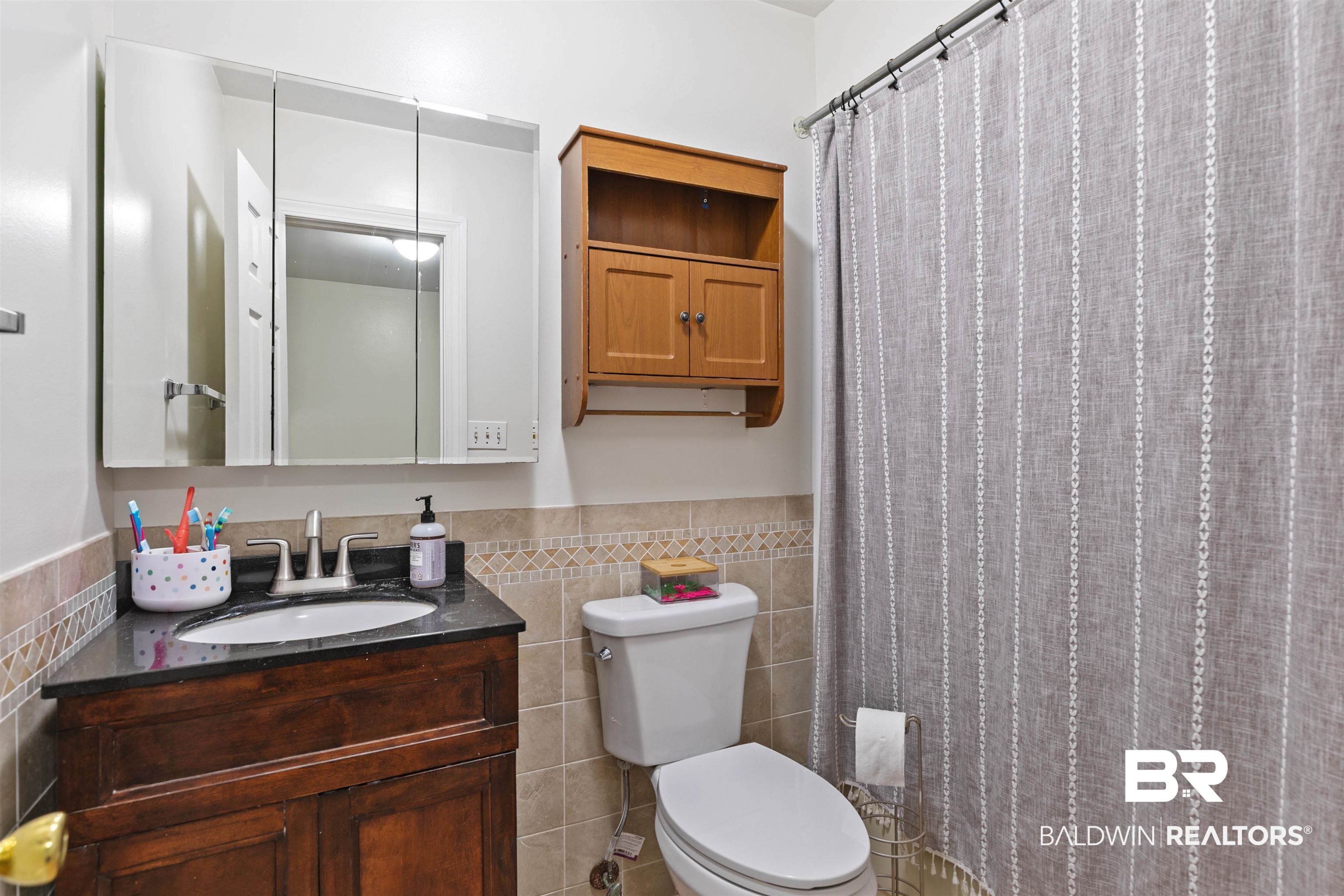 10420 Johnson Road South Mobile, AL 36695 - Photo 30 of 75 Bathroom featuring a dark wood-finish vanity with a dark countertop and integrated sink, a mirrored medicine cabinet, and tiled walls