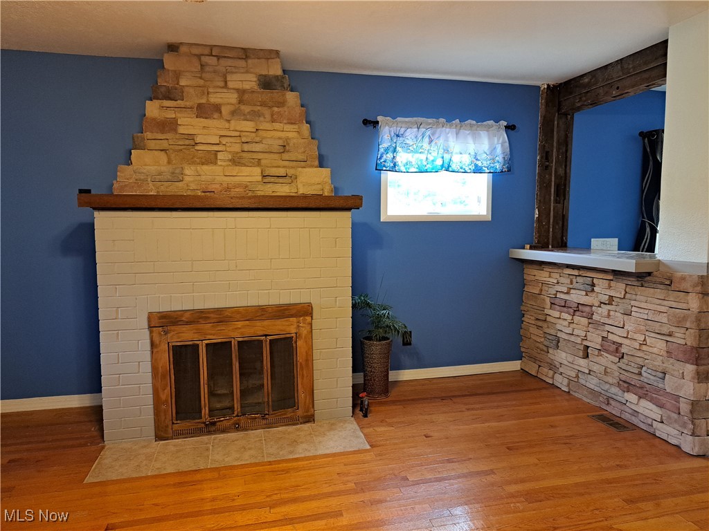 49197 John Tomcho Road Cumberland, OH 43732 - Photo 11 of 50 Unfurnished living room with wood-type flooring and a stone fireplace