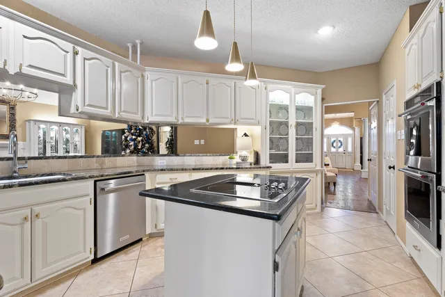 a kitchen with granite countertop a sink a counter top space stainless steel appliances and cabinets