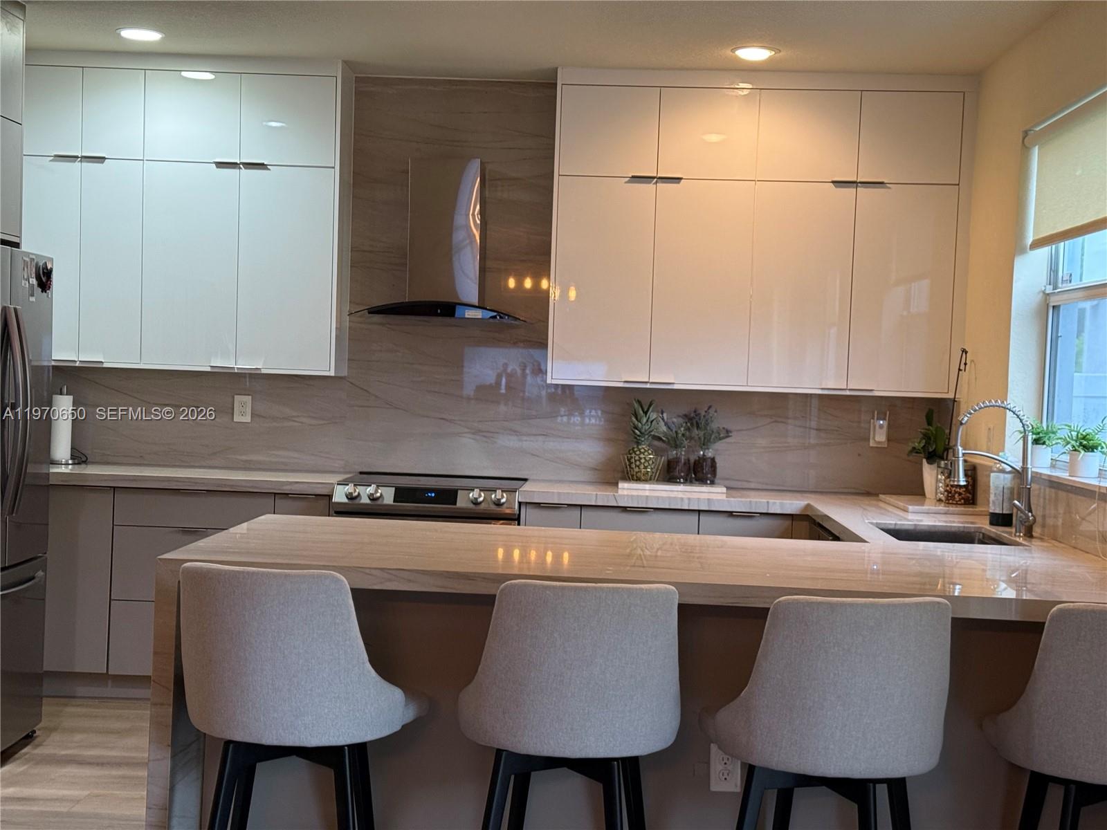 17012 Southwest 91st Street Miami, FL 33196 - Photo 2 of 22 a kitchen with stainless steel appliances a table chairs refrigerator and sink