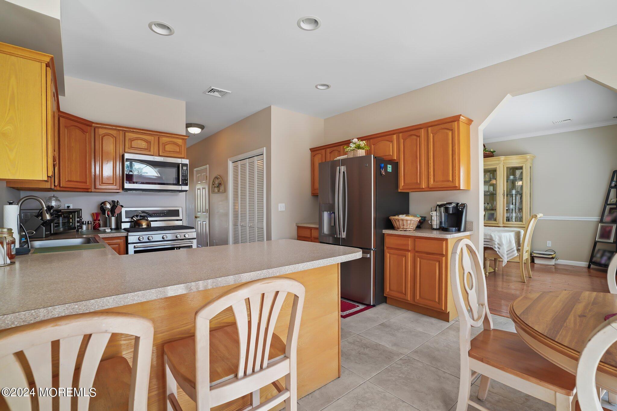 4 Anderson Street Union Beach, NJ 07735 - Photo 16 of 51 a large kitchen with stainless steel appliances granite countertop a refrigerator a stove a sink a dining table and chairs with wooden floor