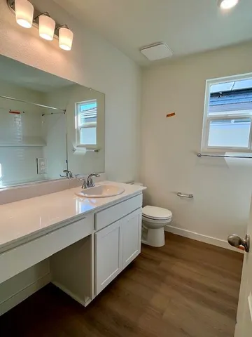 a bathroom with a granite countertop sink a toilet and a mirror