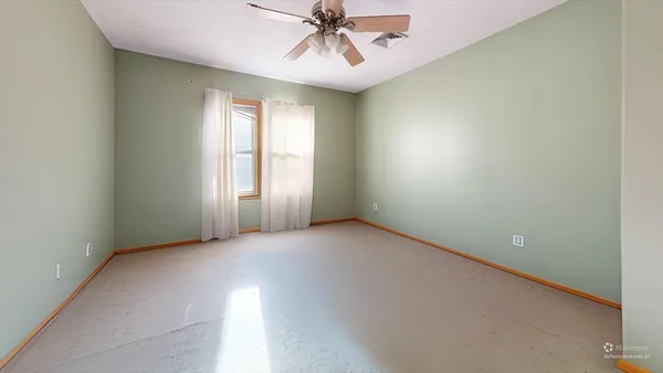 an empty room with windows and fan