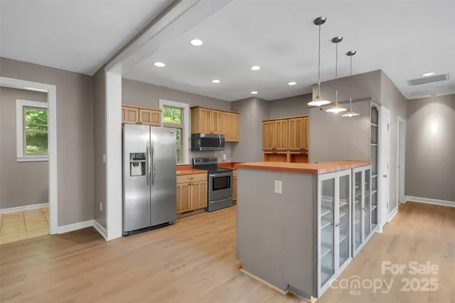 a kitchen with stainless steel appliances granite countertop a refrigerator a sink a stove and a wooden floors