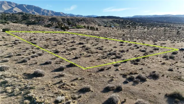 a view of a dry field with mountains in the background