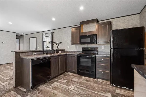 a kitchen with granite countertop a refrigerator stove and sink
