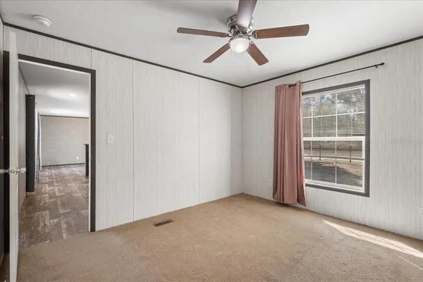 an empty room with windows and fan