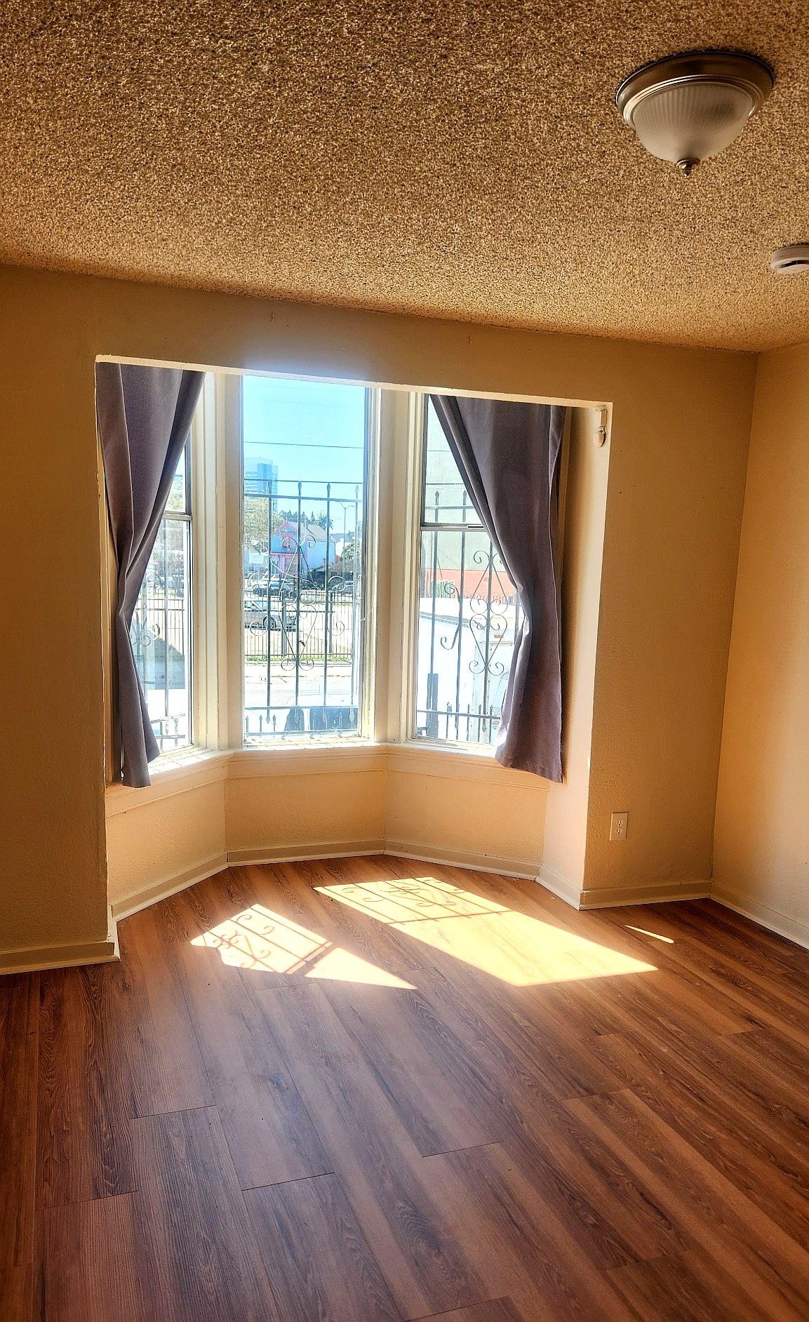 874 Isabella Street Oakland, CA 94607 - Photo 6 of 9 an empty room with wooden floor and windows