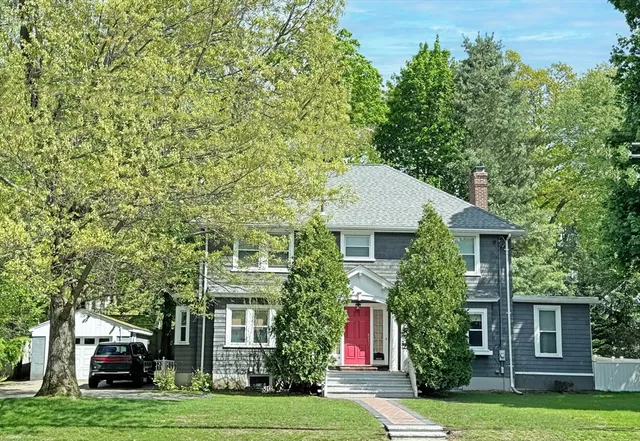 a front view of a house with a garden and trees