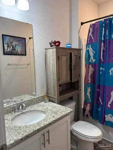 a bathroom with a granite countertop toilet sink and mirror