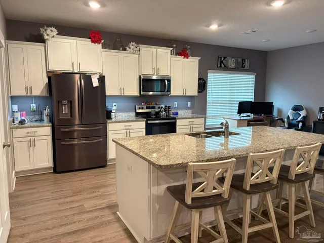 a kitchen with stainless steel appliances granite countertop a refrigerator a stove a sink and a microwave