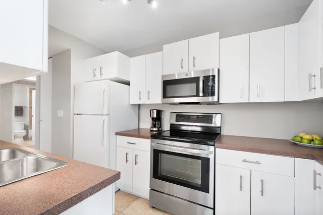 a kitchen with white cabinets and stainless steel appliances