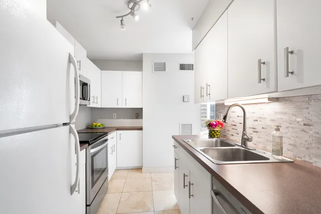a kitchen with granite countertop a sink stainless steel appliances and cabinets