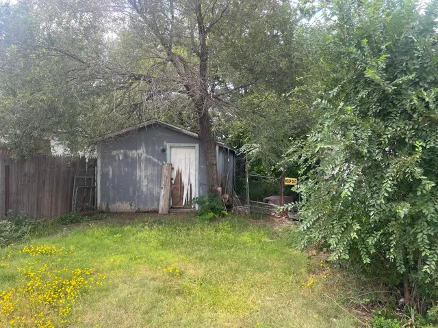 a view of a small yard with large tree and wooden fence